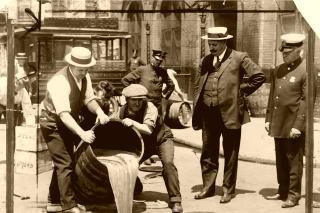 Agents pour a raided cellar of liquor into a New York sewer while Deputy Police Commissioner John A. Leach watches, around 1921